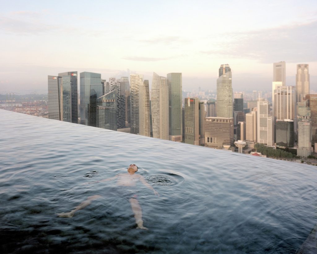  A man floats in the 57th-floor infinity pool  with the skyline of Singapore’s financial district behind him.  Photo: Paolo Woods and Gabriele Galimberti
