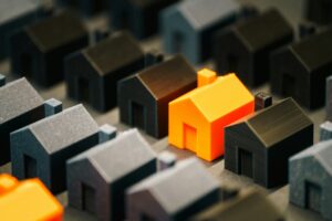 A miniature 3D printed orange house in a row of black miniature 3D printed house