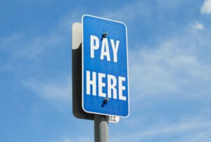 A blue street sign that says 'pay here' on a sunny day
