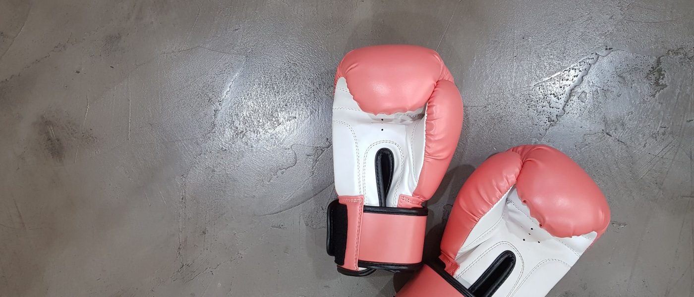 A pair of pink and white boxing gloves on a grey floor