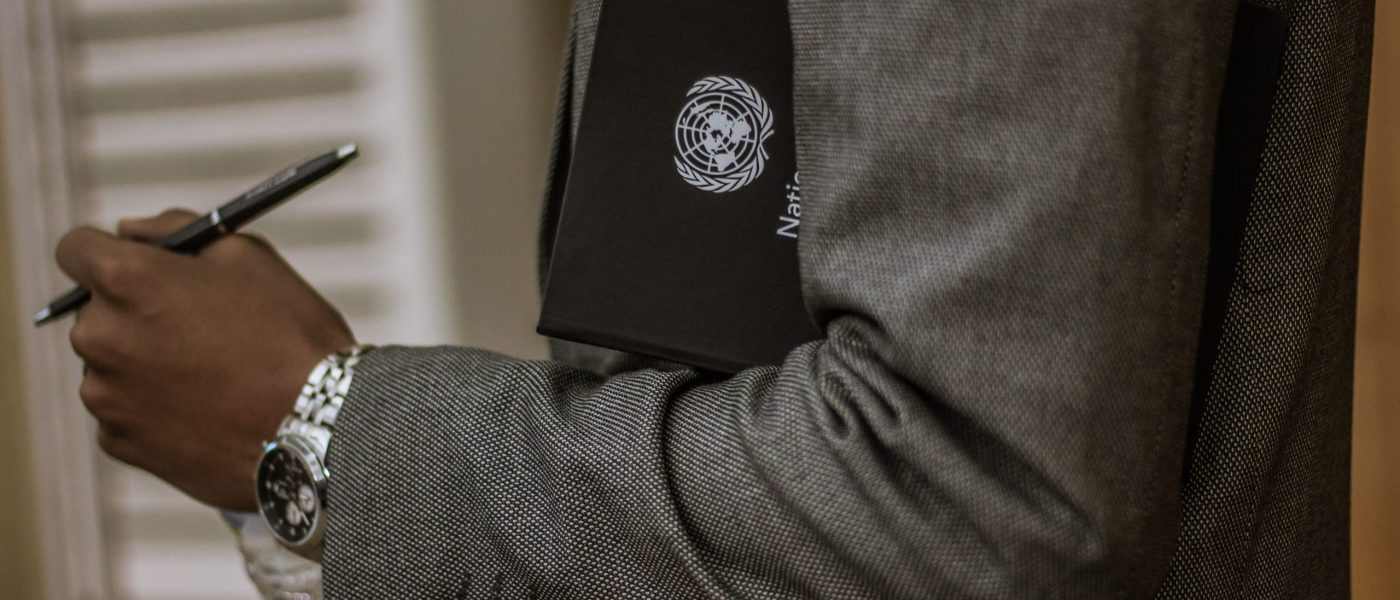 A man in a suit holding a UN-labelled folder.