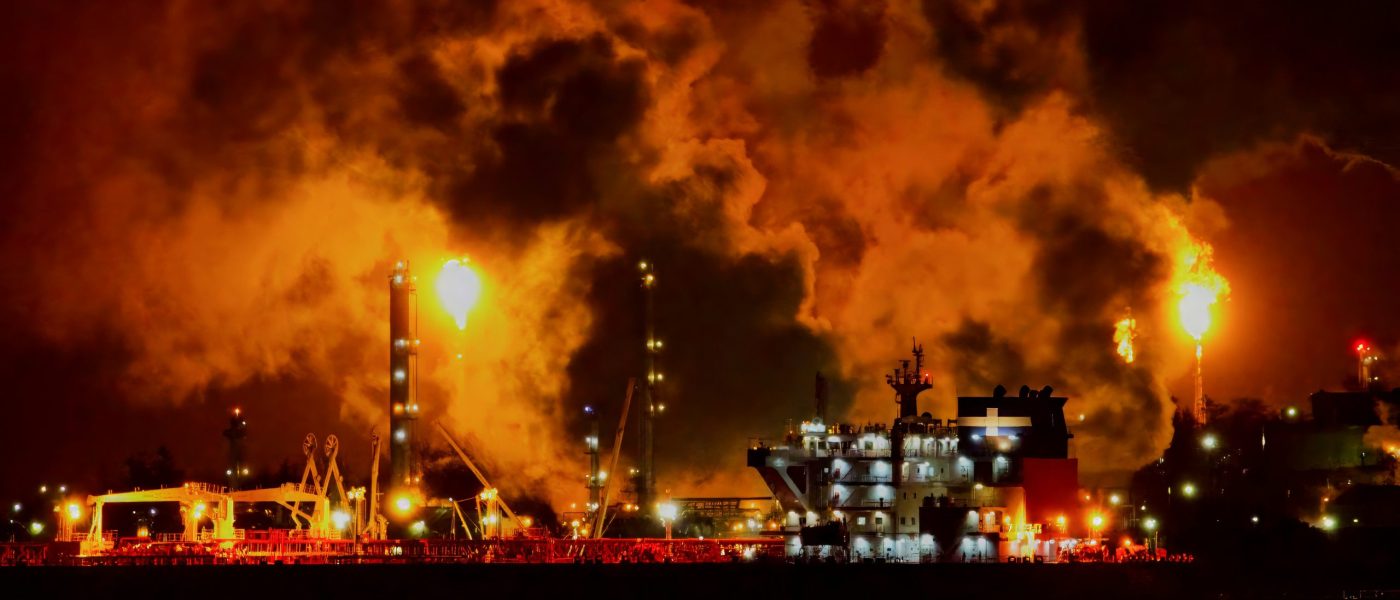 Towers at an oil refinery emit large flames and plumes of smoke in the night - UNSPLASH Towers at an oil refinery emit large flames and plumes of smoke in the night