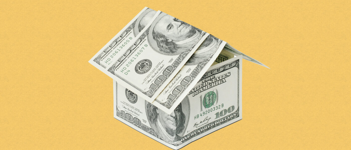A house made of US dollar bills against a yellow background.