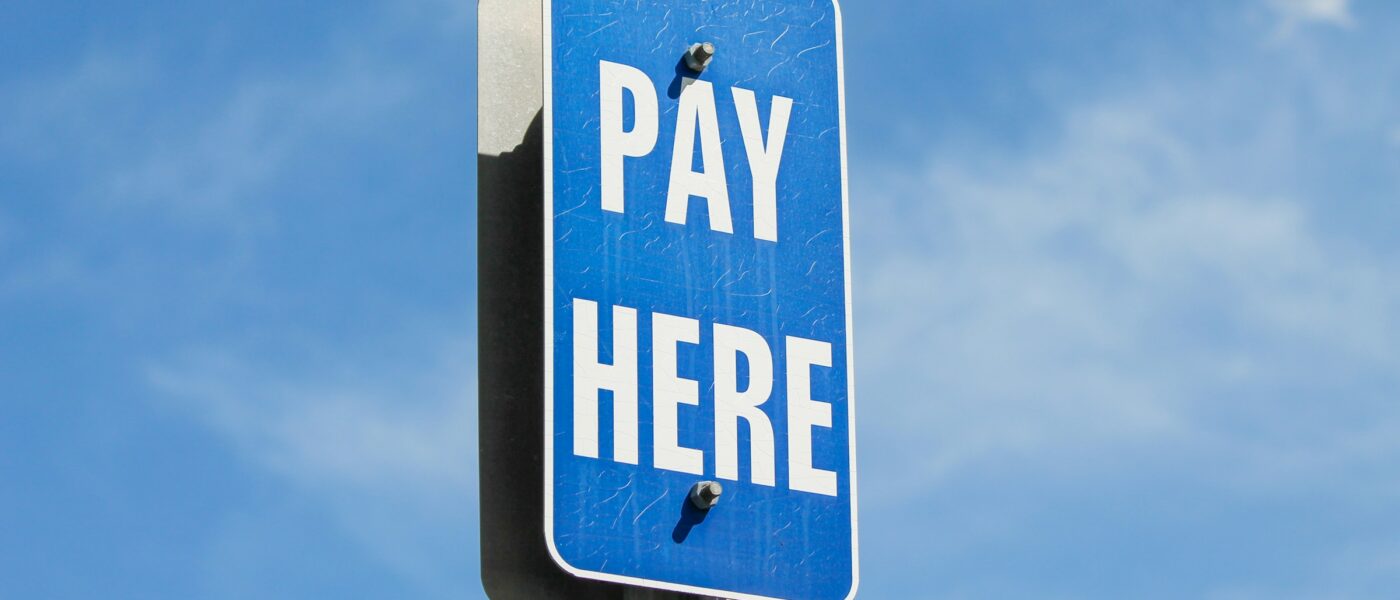 A blue street sign that says 'pay here' on a sunny day - UNSPLASH A blue street sign that says 'pay here' on a sunny day