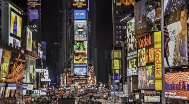 New York Times square at night, brightly lit and busy.