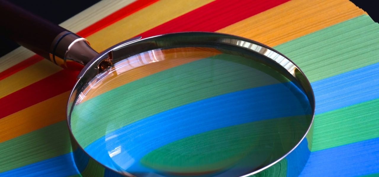 A magnifying glass placed on top of colourful papers