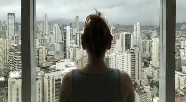 Woman looking at city outside window