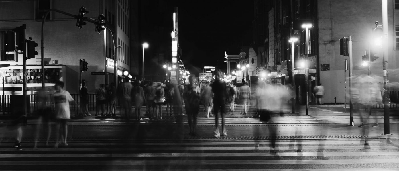 Black and white photo of a blurred people crossing a road