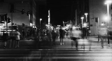Black and white photo of a blurred people crossing a road