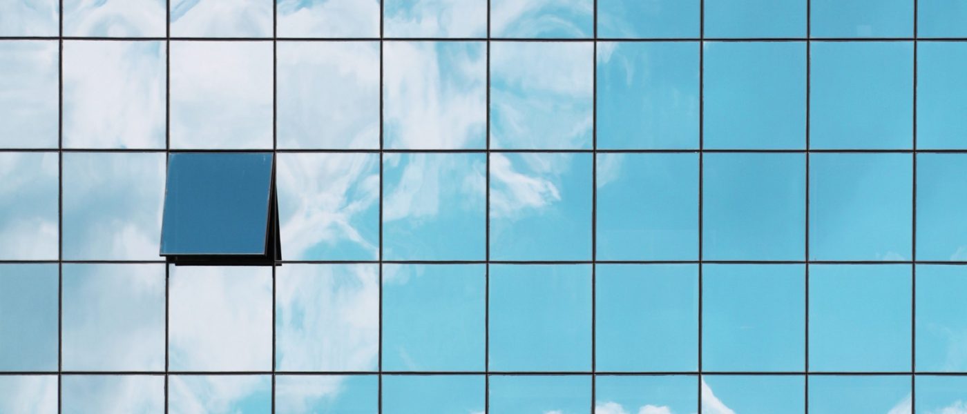 A single open window in a grid of closed glass windows mirroring the sky